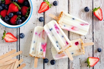 Wall Mural - Group of homemade mixed berry yogurt popsicles. Top view on a rustic white wood background.