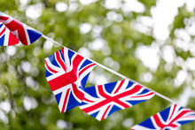 Union Jack Bunting Flapping In The Breeze Celebrating British Event Outside With Trees In The Background In The UK