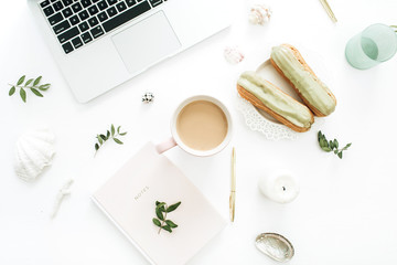 Wall Mural - Home office desk with laptop, pistachio cakes, coffee mug, leaves, sea shells on white background. Flat lay, top view still life concept.