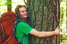 Man With Dreadlocks Hugging A Tree In The Forest
