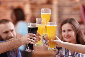 Wall Mural - Friends clinking glasses with beer in sport bar