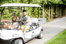 Young And Happy Couple Having Fun Driving A Golf Cart During The Summer Sport Activity