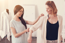 Professional Approach. Young Beautiful Dressmaker Measuring Arms Of Positive Woman While Being Precise And Careful