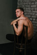© Skripnik Olga - Casually handsome. Studio shot of handsome young man sitting on the chair and looking at camera. bare chest