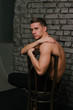 © Skripnik Olga - Casually handsome. Studio shot of handsome young man sitting on the chair and looking at camera. bare chest