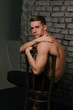 © Skripnik Olga - Casually handsome. Studio shot of handsome young man sitting on the chair and looking at camera. bare chest