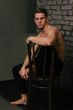 © Skripnik Olga - Casually handsome. Studio shot of handsome young man sitting on the chair and looking at camera. bare chest