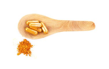 Wall Mural - Turmeric capsules with wooden spoon isolated on white.