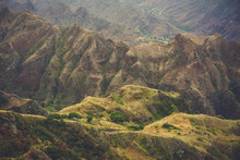 Overview Of Vertiginous Mountains Ridge With Some Dwellings, Valleys And Peaks Covered With Yellow Grass And Green Mango Trees
