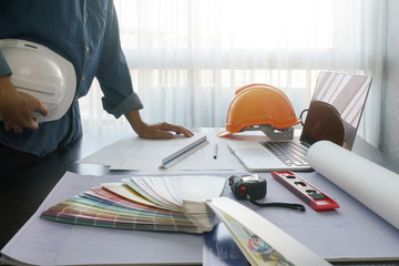 architect working on table with blueprint and construction tools - business and industrial concept