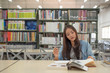 © Phimchanok - pretty woman happy to read and research in library