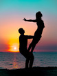 © kohanova1991 - Silhouette of young woman and man doing pair yoga on sea beach at sunset. Meditation. Couple practicing acro yoga. Flexibility workout at nature background.