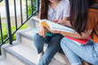 © Shutter2U - Close up of two Asian beauty girls reading and tutoring books for final examination together. Student smiling and sitting on stair. Education and Back to school concept. Lifestyles and People theme.