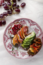 Variety Of Bruschettas With Avecado, Prosciutto, Tomatoes And Pomegranate Seeds On Vintage Porcelain Plate