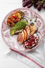 Variety Of Bruschettas With Avecado, Prosciutto, Tomatoes And Pomegranate Seeds On Vintage Porcelain Plate