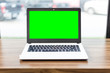 © Thinapob - Green screen of Mockup image of laptop with blank screen on wooden table.