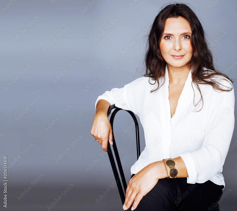 pretty brunette confident mature woman sitting on chair in studi Stock ...