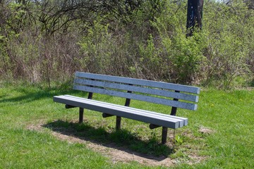 The metal park bench in the park on a sunny day.