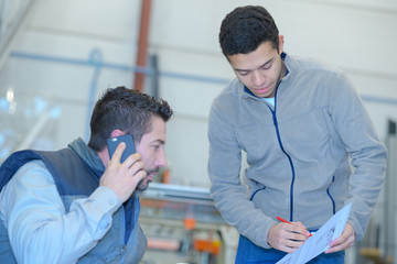 businessman using mobile phone with worker looking paper planes