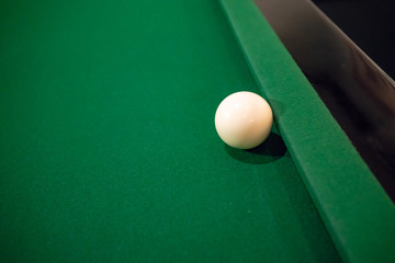 Cue ball on cushion on green snooker table.