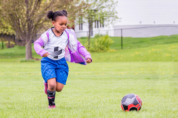 Wall Mural - A young girl is learning how to play soccer	