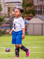 Wall Mural - A young girl is learning how to play soccer	