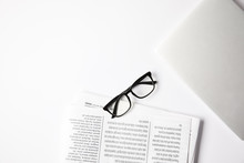 Top View Of Eyeglasses, Laptop And Newspapers On White Table