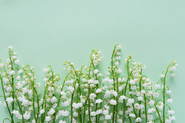 Wall Mural - Romantic gentle flower background, lily of the valley on a mint color  background, top view, flat layout. 