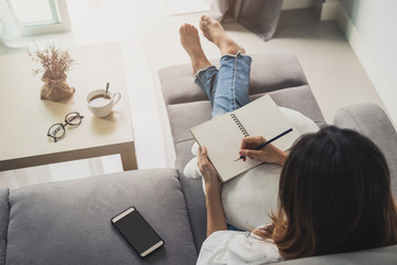 Young woman using smartphone at cozy home on sofa in living room