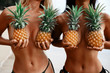 two incredibly beautiful sexy girl models in a bikini on the beach of a tropical island, blond brunette, bronze tan, travel summer vacation, fashion style, in the hands of pineapples cover the chest