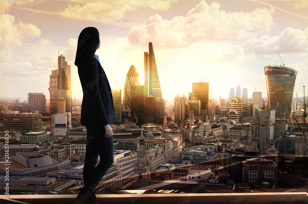 Young woman in suit looking over the City of London at sunrise  - obrazy, fototapety, plakaty 