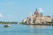 Hungarian Parliament and travel boats sailing the Danube river in Budapest, Hungary.
