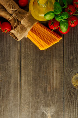 Italian food background with vine tomatoes, basil, spaghetti, olive oil. Top view