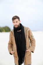 European Male Person With Beard Wearing Coat And Scarf Standing In White Snow Background. Concept Of Fashion And Seasonal Winter Inspiration.