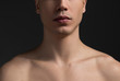 Close up of young male neck and half of face. Topless guy is demonstrating perfect healthy soft skin. Dark wall in background. Skincare concept
