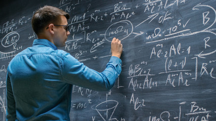 Brilliant Young Mathematician Approaches Big Blackboard and Finishes writing Sophisticated Mathematical Formula/ Equation.
