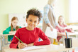 © pressmaster - Happy schoolboy looking at camera while carrying out final exam test at lesson