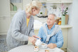 © pressmaster - Senior female in grey woolen cardigan pouring tea from teapot into her husband cup