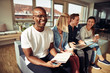 © Flamingo Images - Smiling African businessman sitting with colleagues in a modern