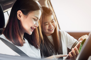 Vacation time and travel, beautiful young women cheerful travels together for a relaxing holiday. And the laughter in the car. Finding directions by map.