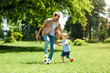 © LIGHTFIELD STUDIOS - dad and son playing football at park