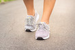 © peerayot - Female runner feet jogging on street.