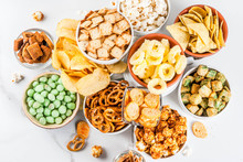Variation Different Unhealthy Snacks Crackers, Sweet Salted Popcorn, Tortillas, Nuts, Straws, Bretsels, White Marble Background Copy Space