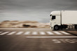 LKW fährt schnell auf einer Straße in der Wüste