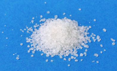 Pile of sugar isolated on blue background, closeup