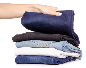 Stack of jeans in hand on a white background isolation