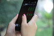 © Oran Tantapakul - Female hand with smartphone trading stock online in coffee shop , Business concept