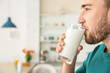 Young man drinking tasty milk at home