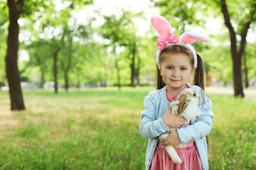 Little girl with adorable bunny outdoors on sunny day. Easter celebration