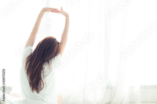 Fotografie, Obraz Beautiful young asian woman stretch and relax in bed after wake up morning at bedroom, back view, new day and resting for wellness, lifestyle concept